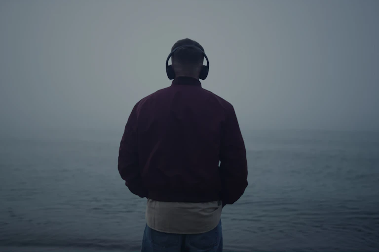 A man listens to headphones while walking in the gloaming.