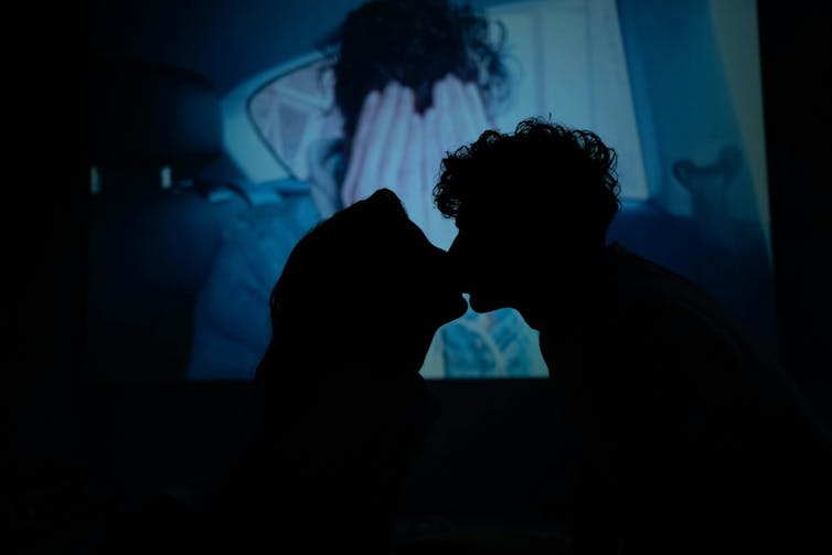 A young womand and a young man kiss.