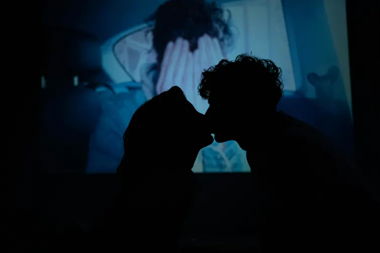 A young womand and a young man kiss.