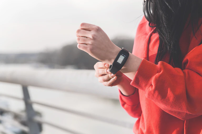 Woman in red top putting a pedometer on her wrist.