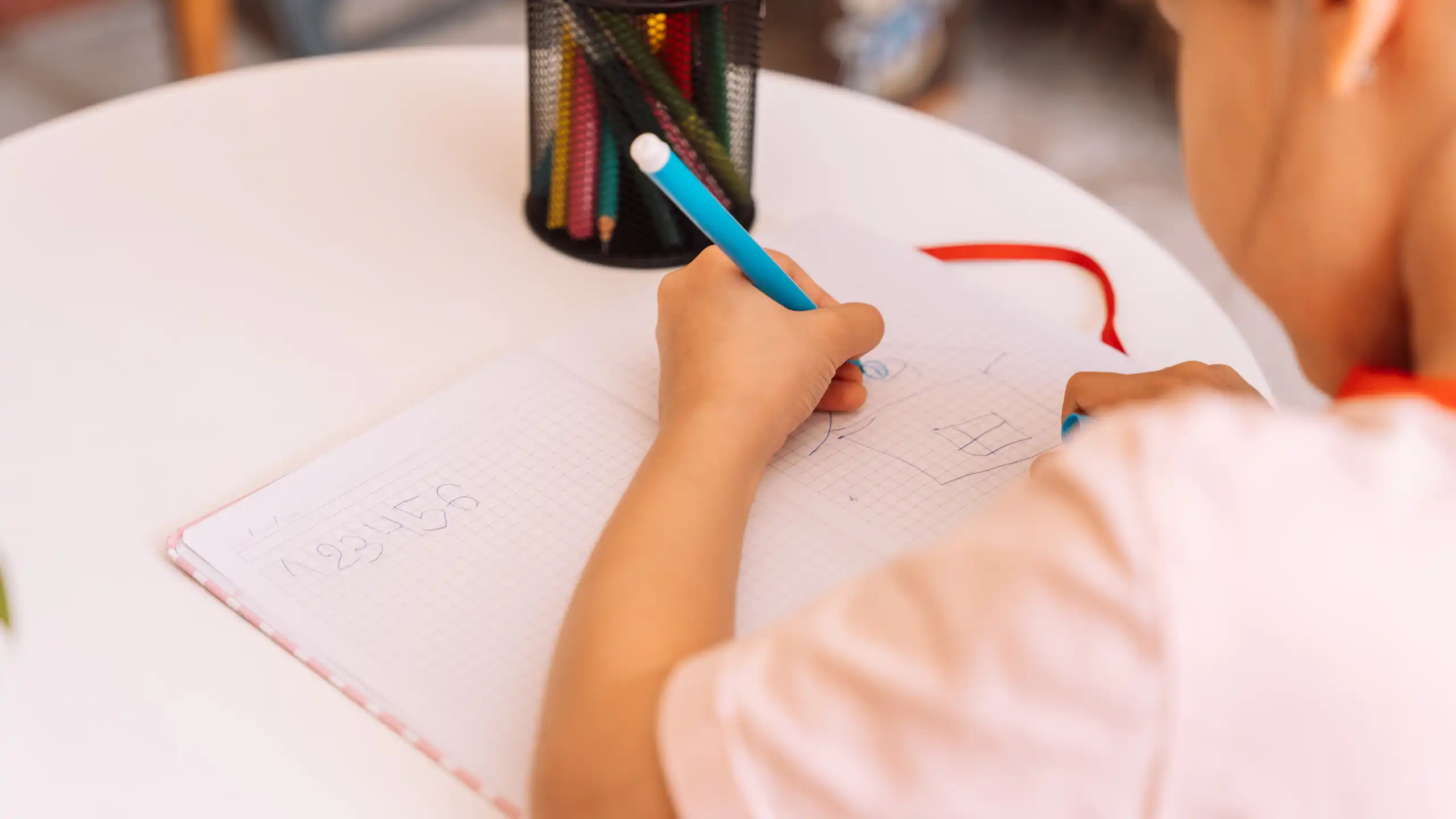 una niña dibuja en un cuaderno con su mano izquierda