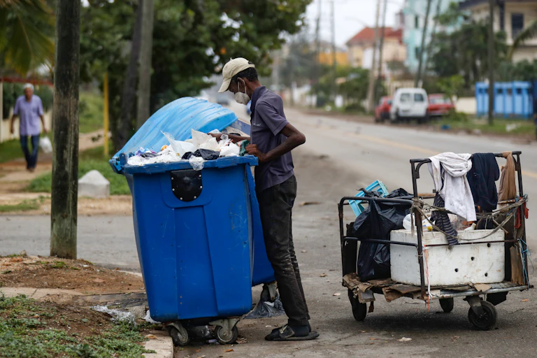 A man searching through a waste bin in Cuba.