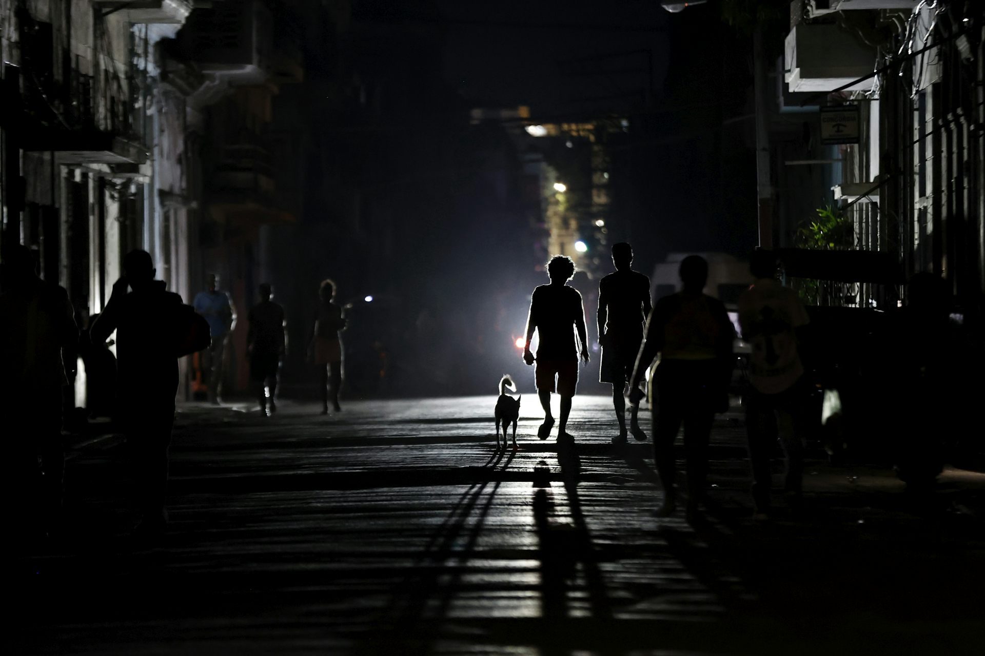 Two people walking a dog during a blackout in Cuba.