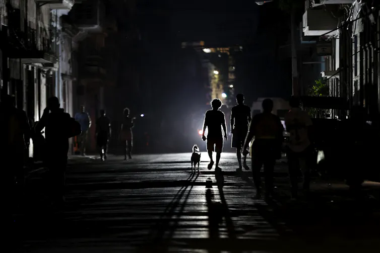 Two people walking a dog during a blackout in Cuba.