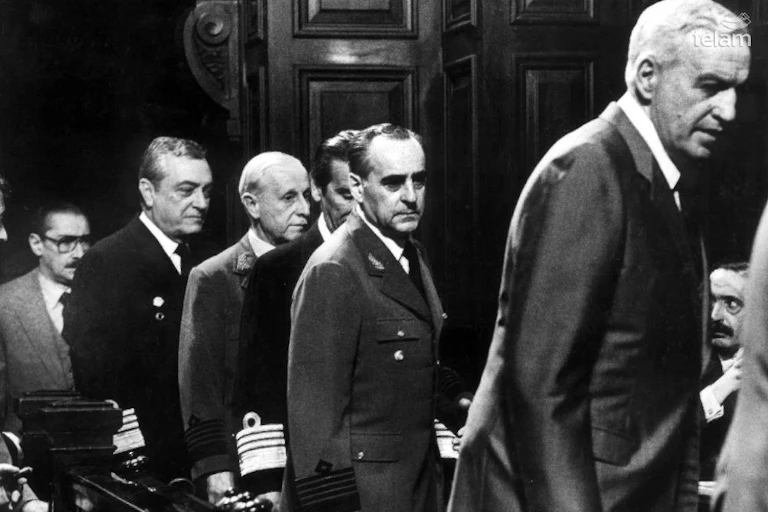 Foto en blanco y negro. Integrantes de la Junta Militar ingresan a la sala de audiencias.