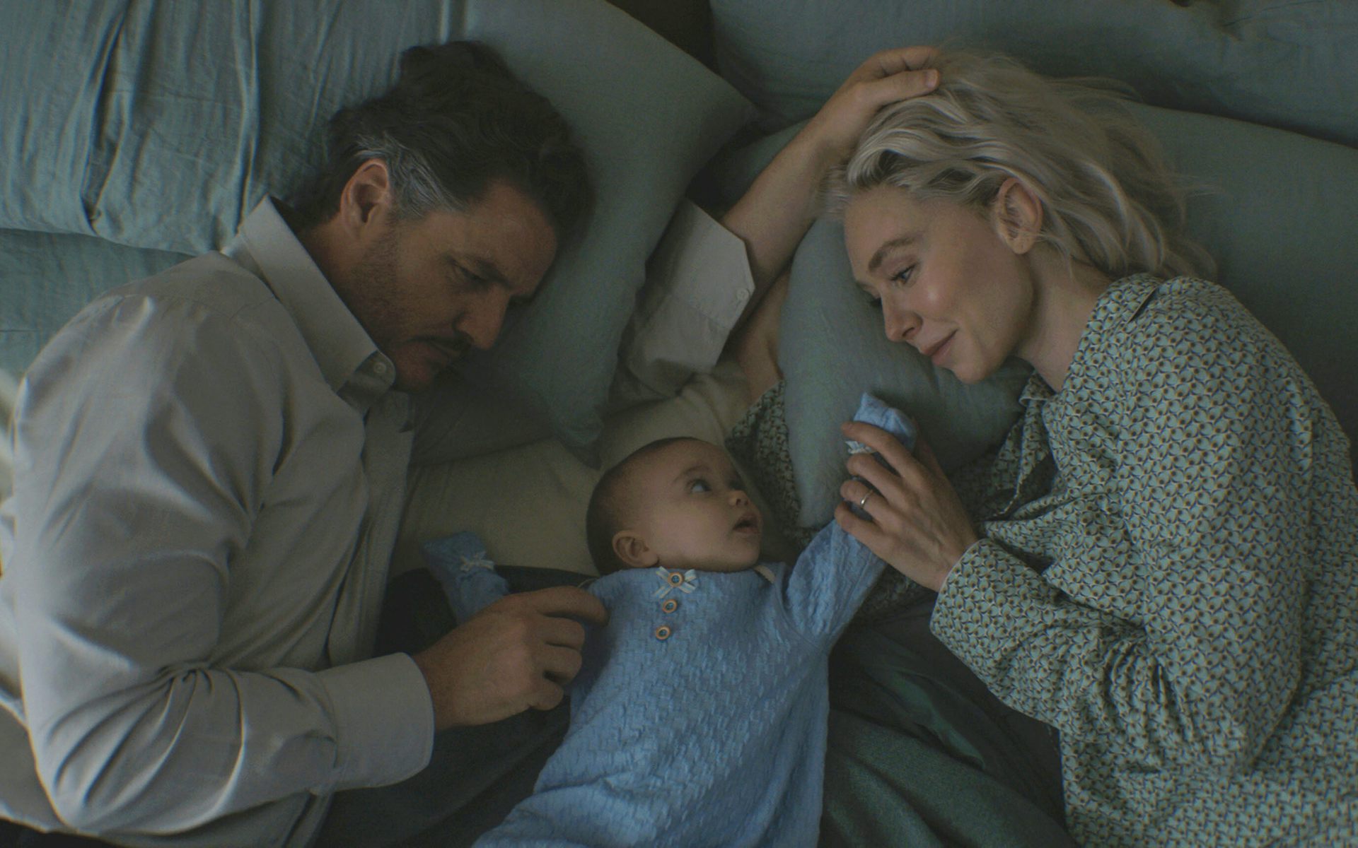 A man and woman with a baby on a bed.