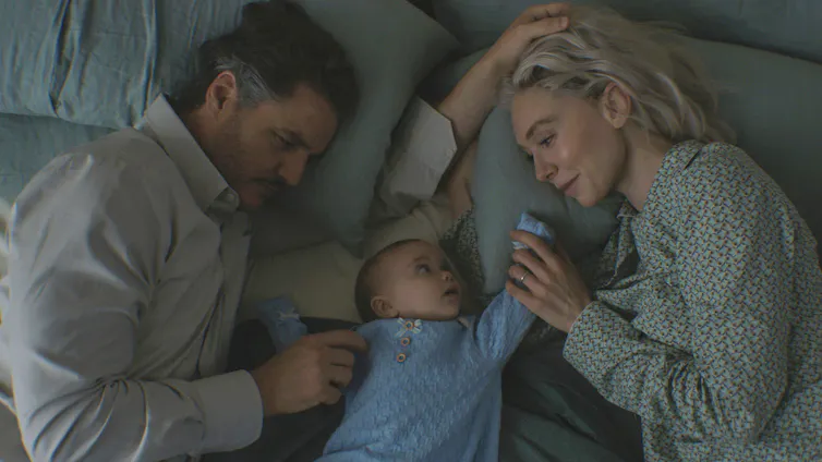 A man and woman with a baby on a bed.