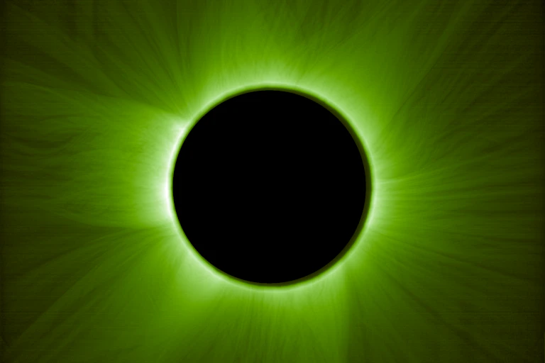 The sun, shown silhouetted behind a dark sphere. All that is visible is a green halo of light.