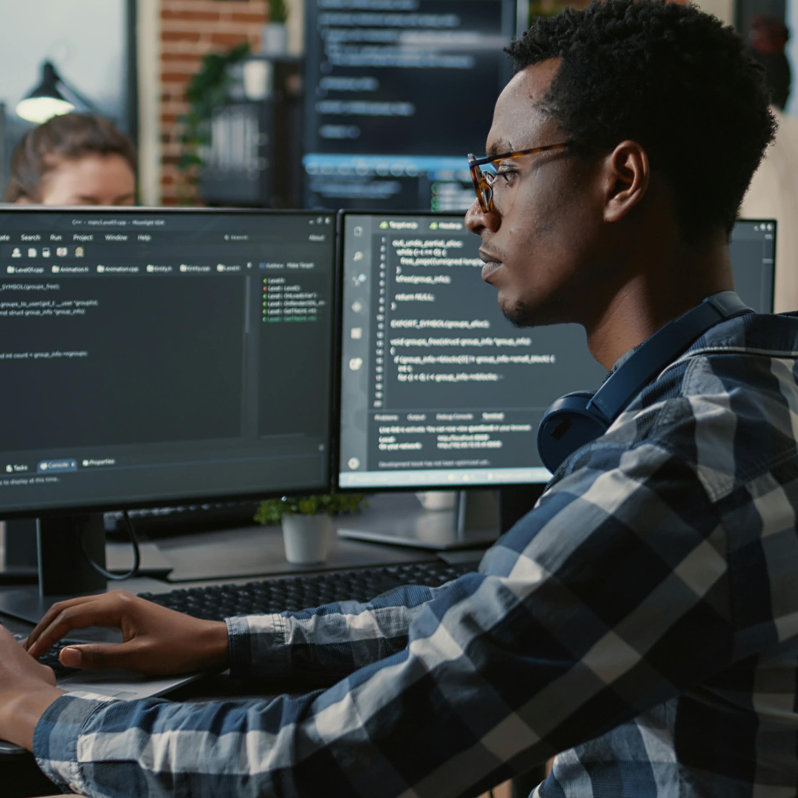 Un homme travaille devant trois écrans d'ordinateur.