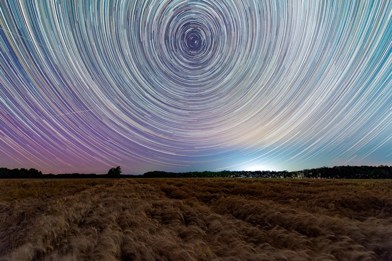 Circular star trails covering the sky over a field