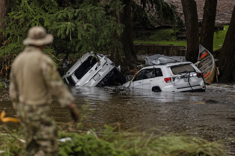 Vehicles sit submerged as a search and rescue worker looks through debris for any survivors or remains of people swept up in the flash flooding on July 6, 2025 in Hunt, Texas.