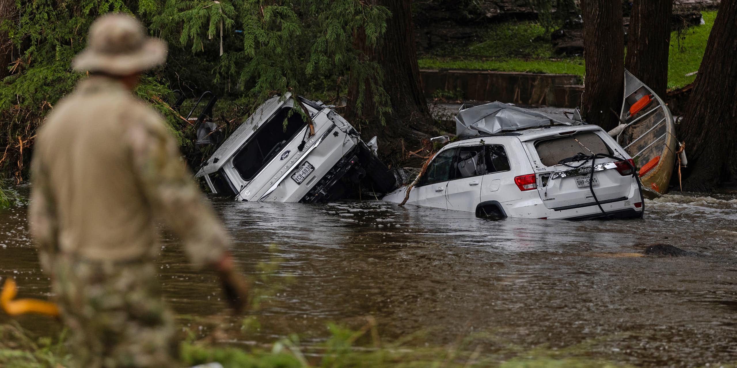 Vehicles sit submerged as a search and rescue worker looks through debris for any survivors or remains of people swept up in the flash flooding on July 6, 2025 in Hunt, Texas.