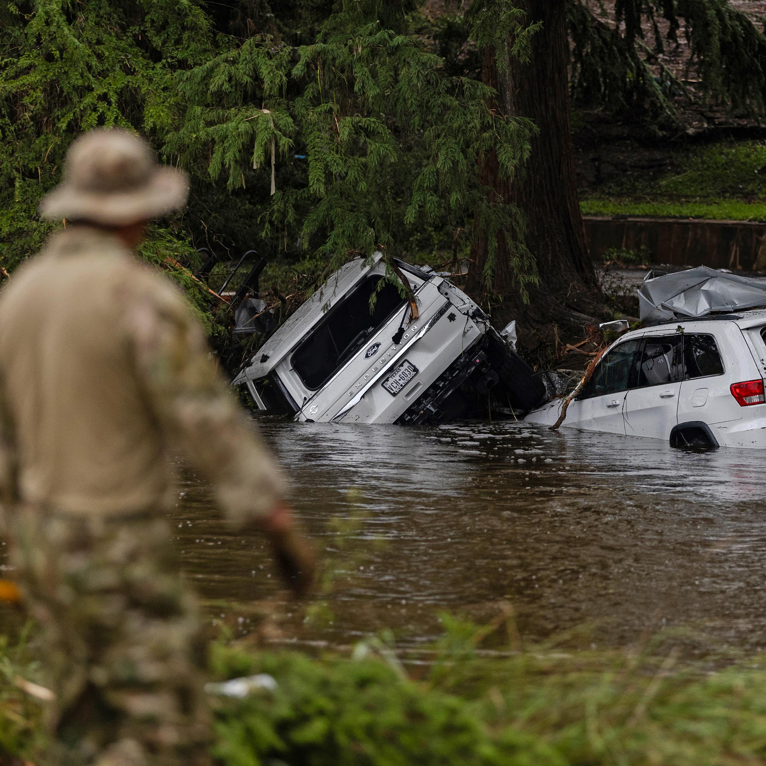 Vehicles sit submerged as a search and rescue worker looks through debris for any survivors or remains of people swept up in the flash flooding on July 6, 2025 in Hunt, Texas.