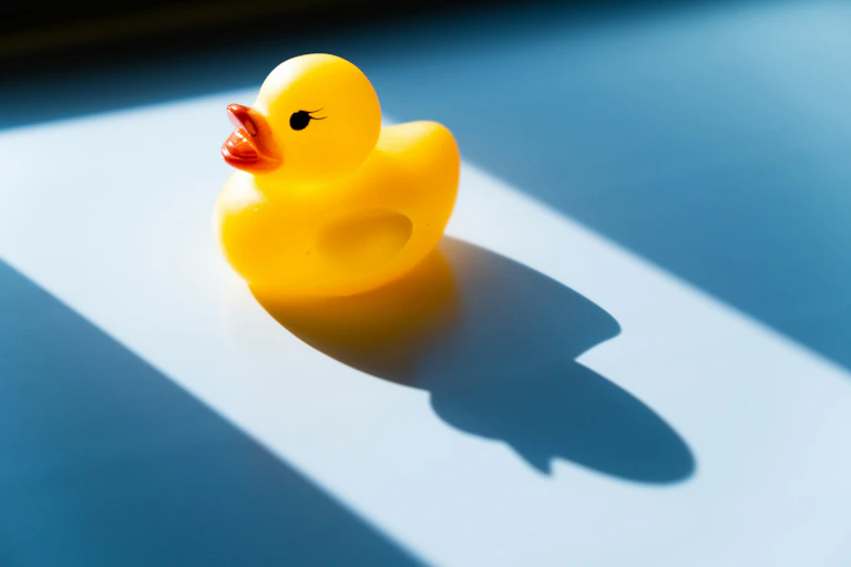 A rubber duck sits on a blue surface.