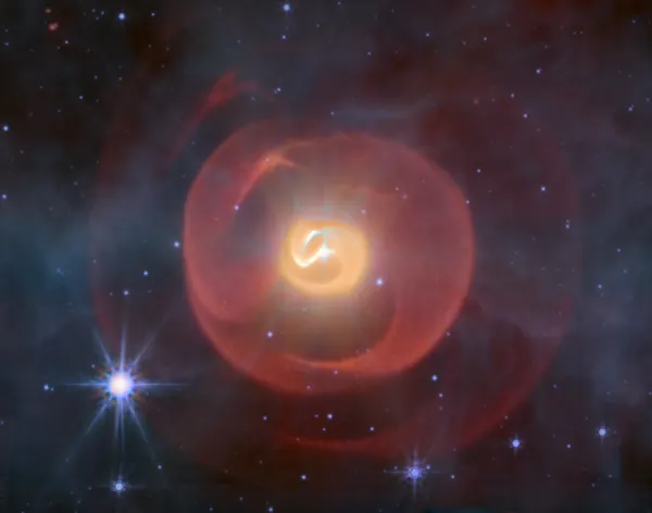 Tres conchas de polvo, que parecen serpientes en espiral, la del medio amarillo y las exteriores rojos contra un fondo de estrellas azules.