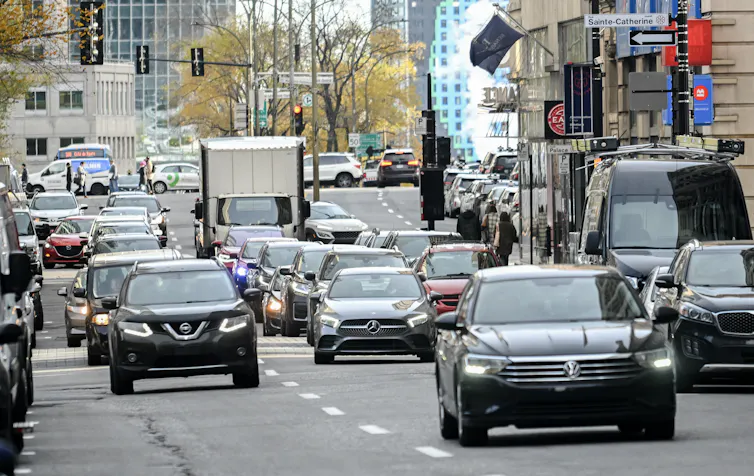 Cars drive down a multi-lane road in a city