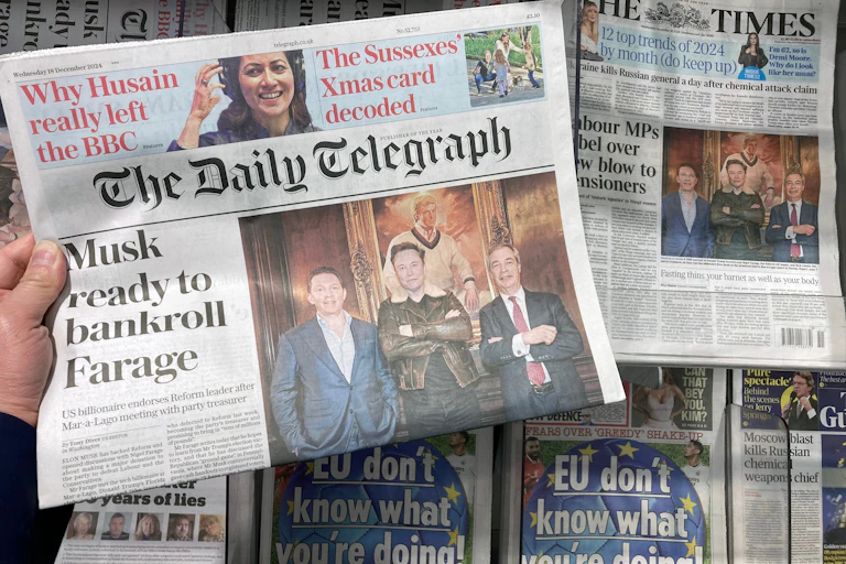 A hand holding up an edition of the Daily Telegraph, featuring a front page story about Elon Musk possibly funding Nigel Farage's Reform UK