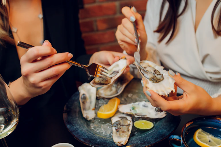 Two people eating oysters.