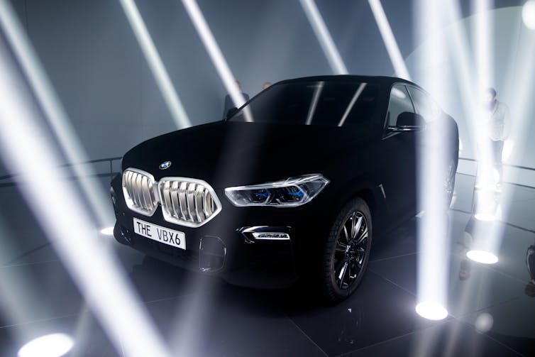 Very black car surrounded by spotlights