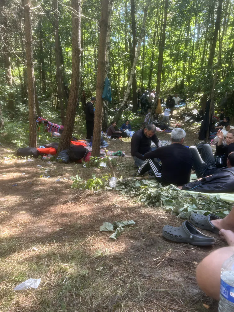 Plusieurs personnes sont assises à même le sol dans une forêt