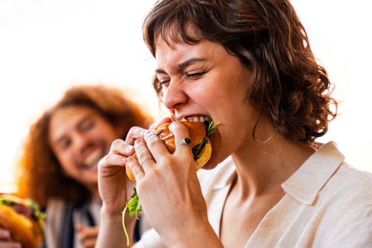 woman biting into burger with bread bun