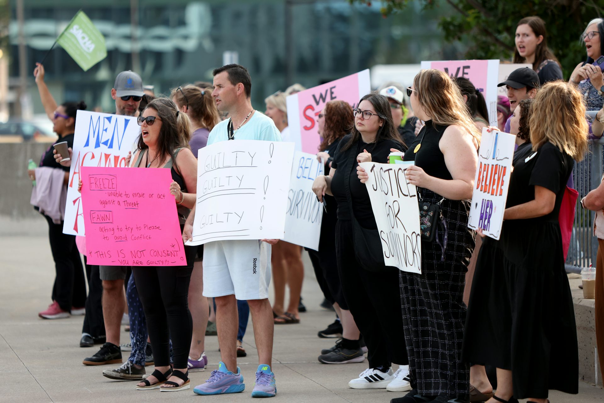 A crowd of protesters holding signs in support of the victim of the Hockey Canada sexual assault trial  