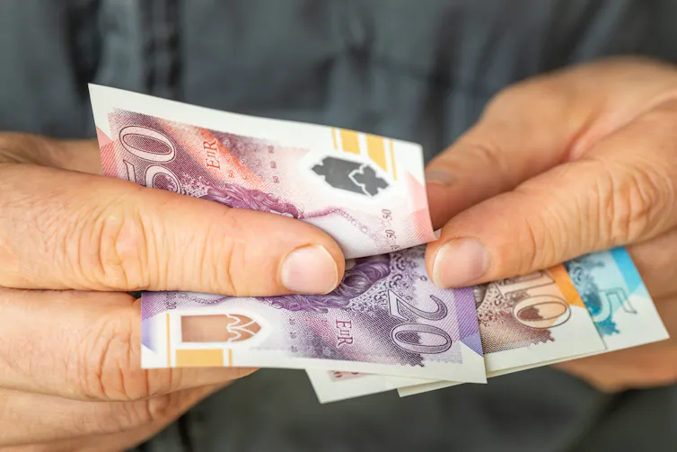 A pair of hands flipping through British notes