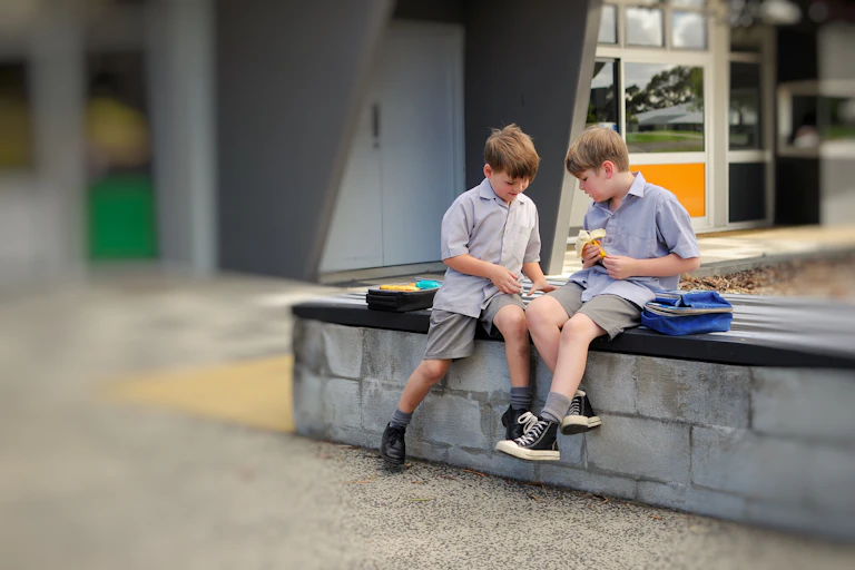 A child turns to speak to another boy at recess in a school playground.