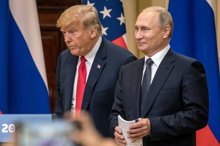 Two men in suits stand next to each other.