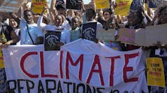 A group of people protesting and holding up a banner that says Climate Reparations Now