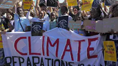 A group of people protesting and holding up a banner that says Climate Reparations Now