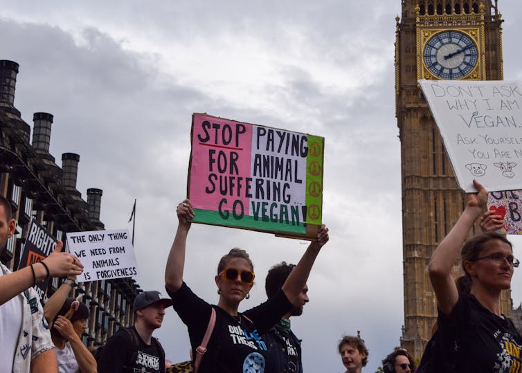 a woman in a crowd holds a sign over her head
