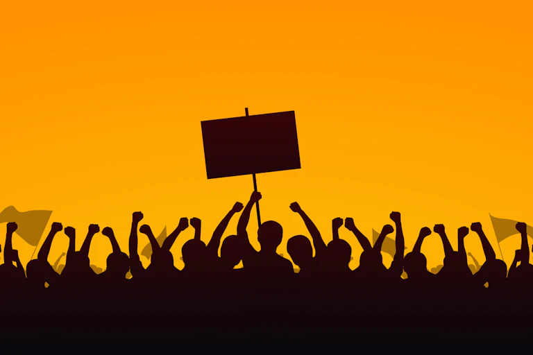 A silhouette of a group of people raising their fists and holding a protest sign aloft against a deep yellow background.