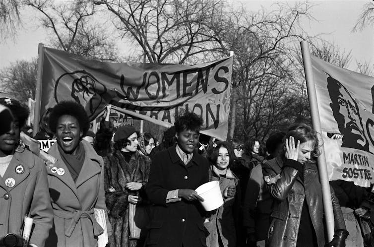 A group of women, several of whom carry a 'Women's Liberation' banner