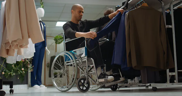 man using a manual wheelchair looking at shirts in a clothing shop