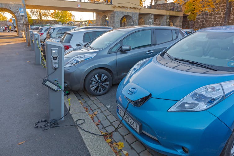 Cars plugged into public chargers on a city street.