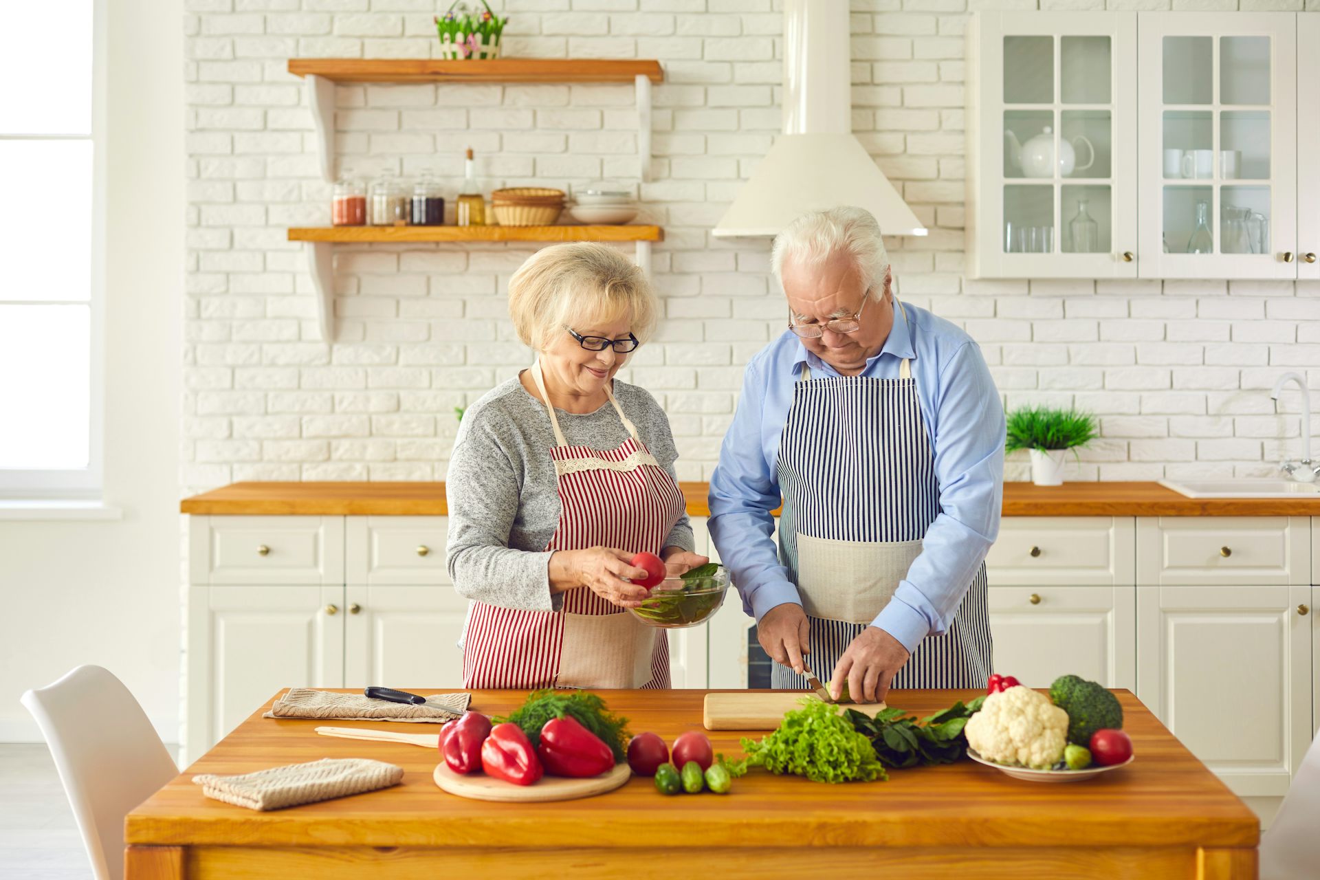 Couple de personnes âgées préparant ensemble un repas santé dans la cuisine.