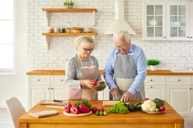 Couple de personnes âgées préparant ensemble un repas santé dans la cuisine.