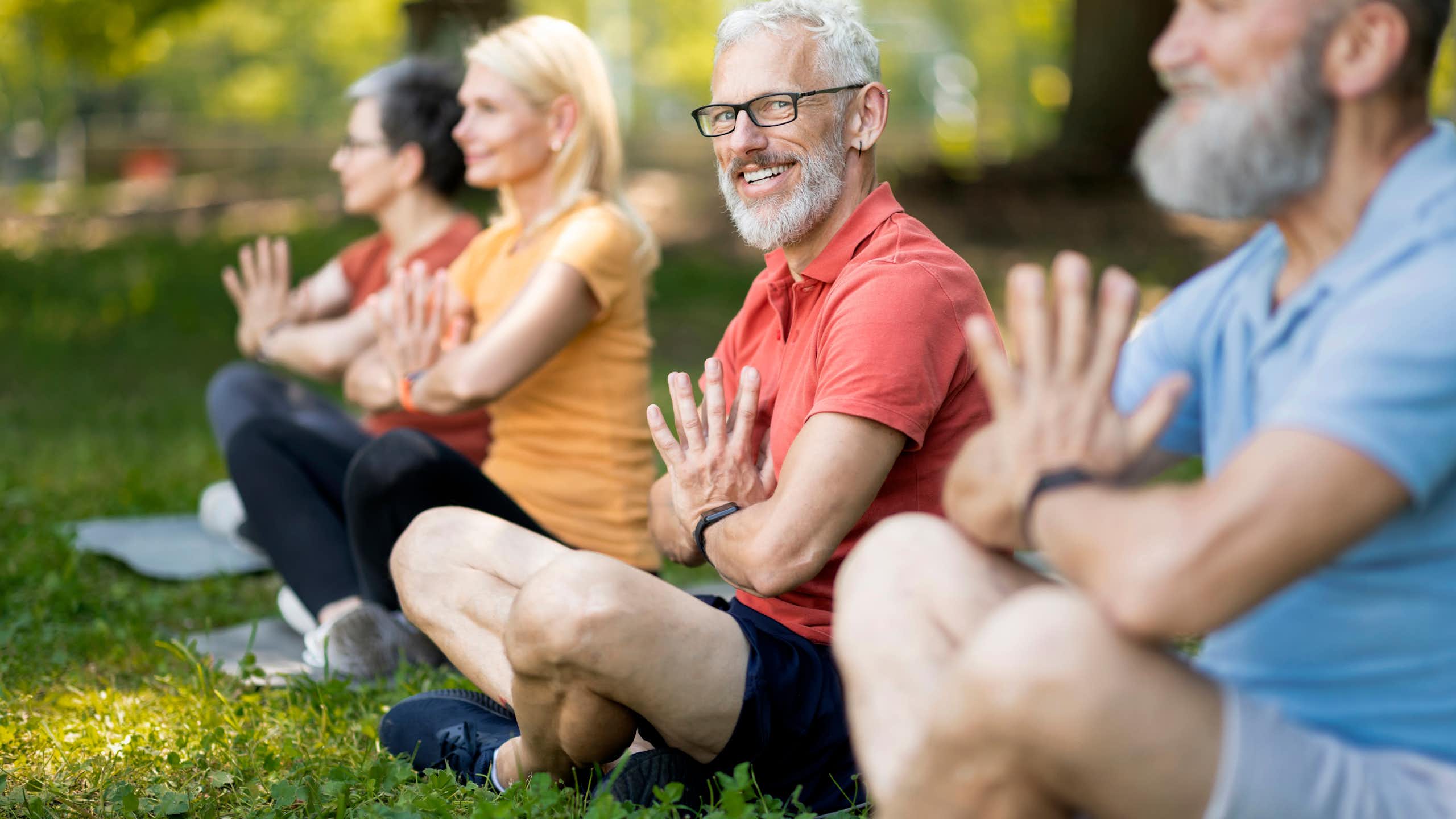 Portrait d'un senior pendant un cours de yoga collectif en extérieur.