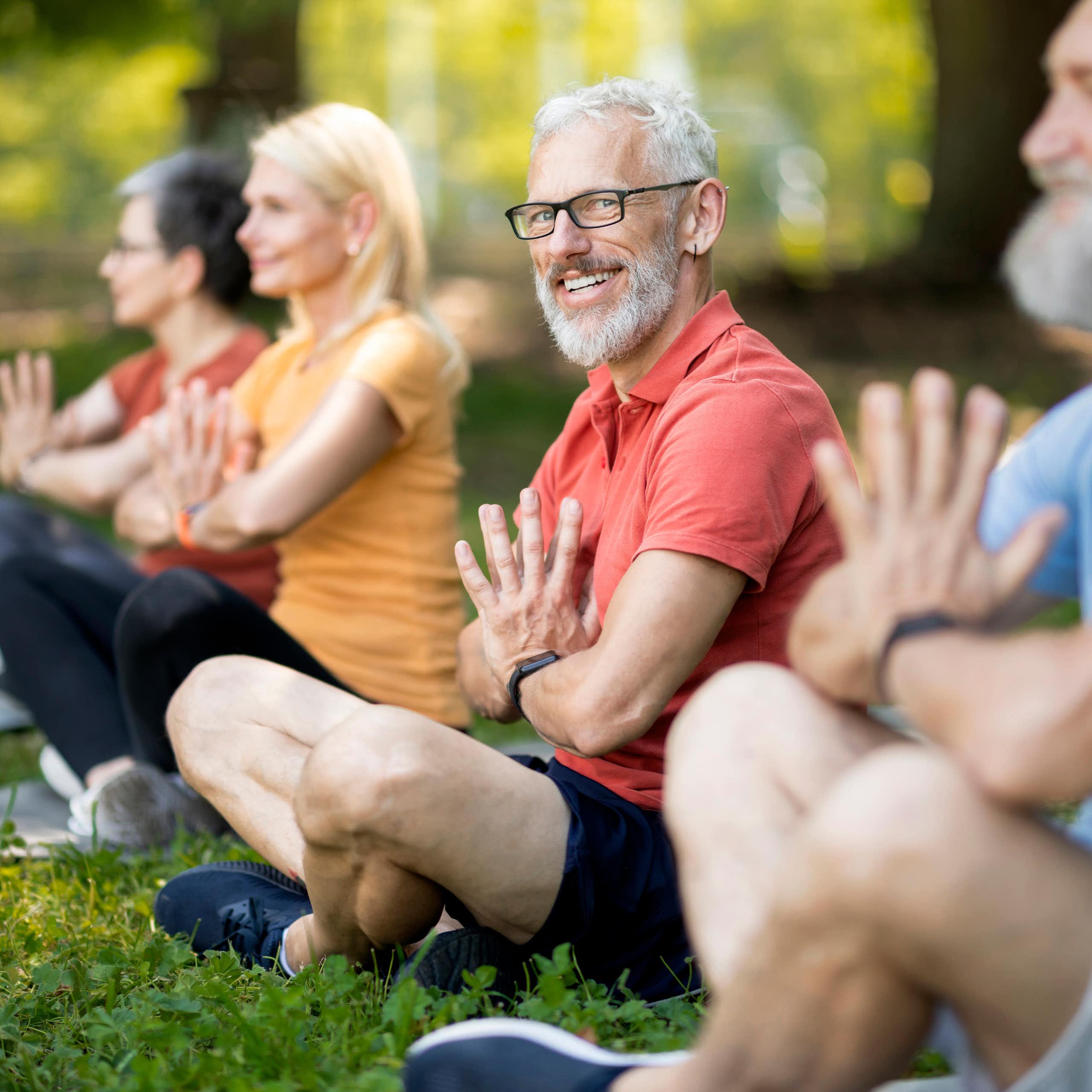 Portrait d'un senior pendant un cours de yoga collectif en extérieur.