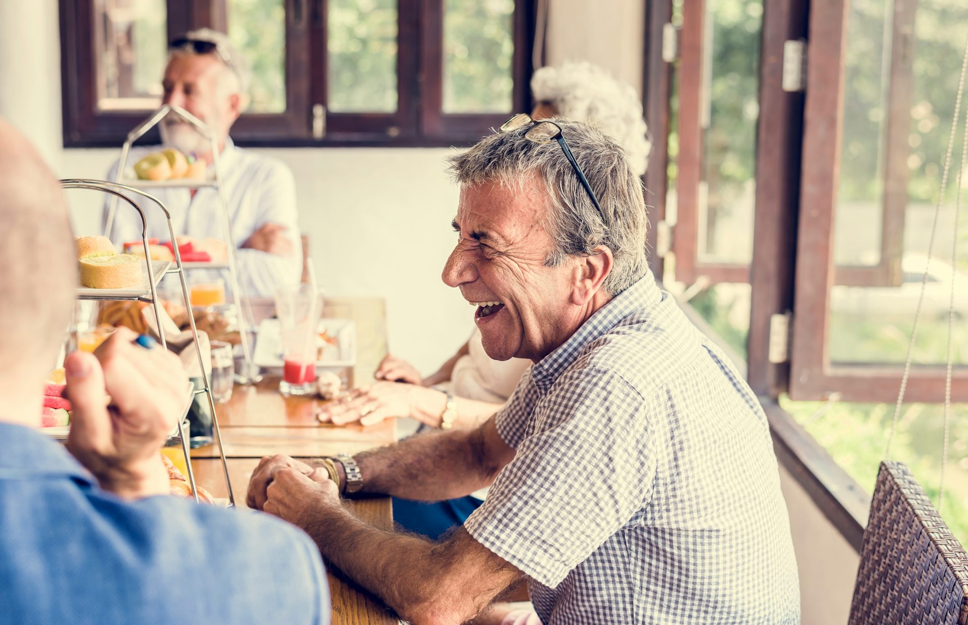 Older man laughs with friends at morning tea