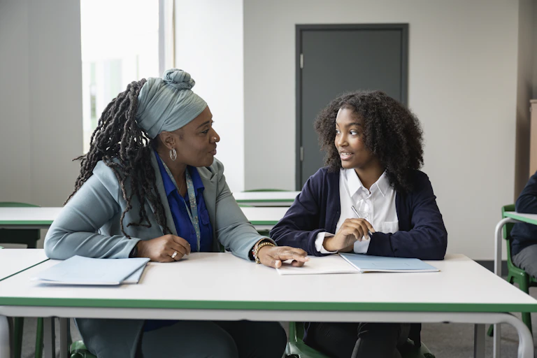 Older woman sits at table talking with young female student