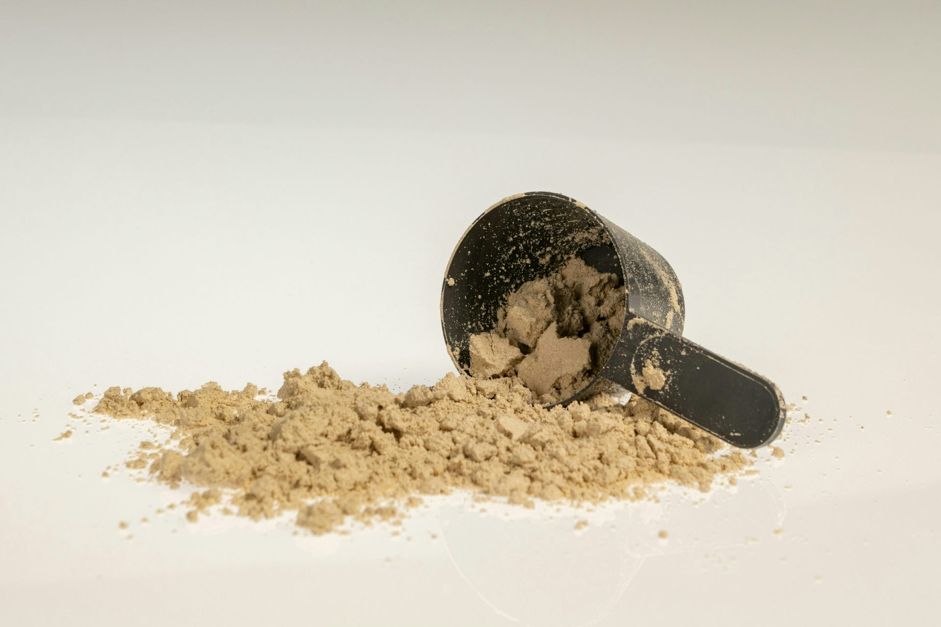 A scoop with a small pile of beige powder