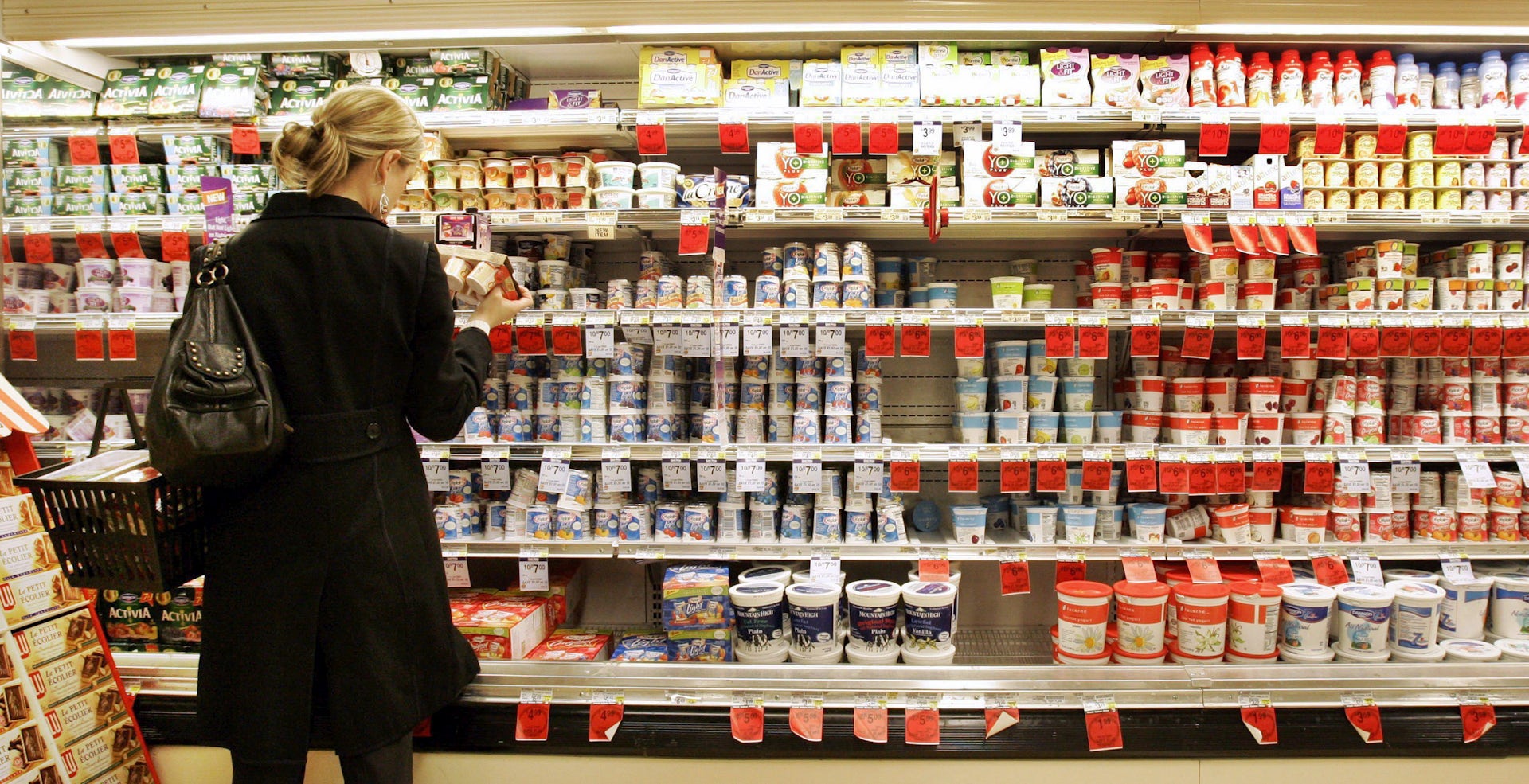 A shopper selecting a product from the dairy aisle in a supermarket