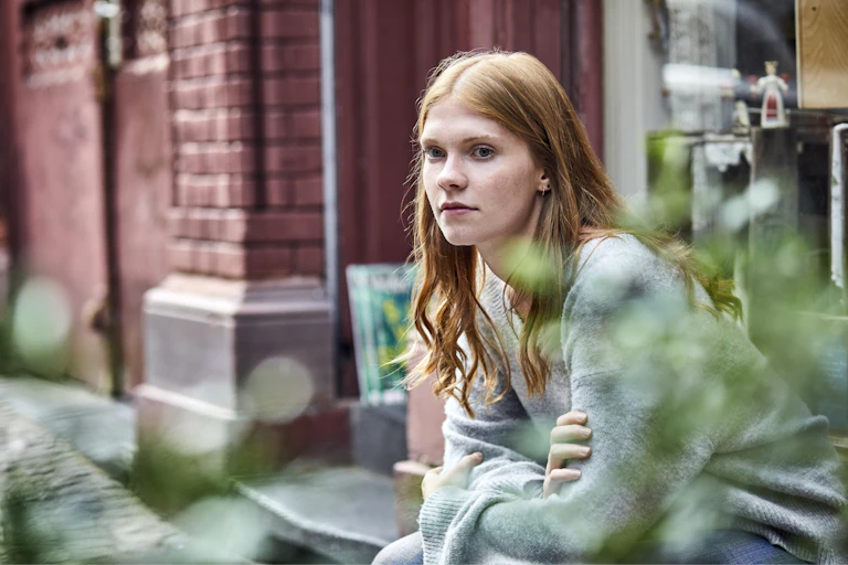 A young woman sitting on a step.