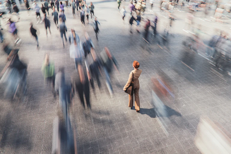 A woman stands alone in a busy city.