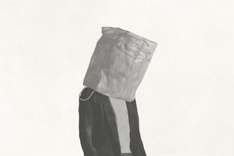 A man walks with a paper bag on his head.