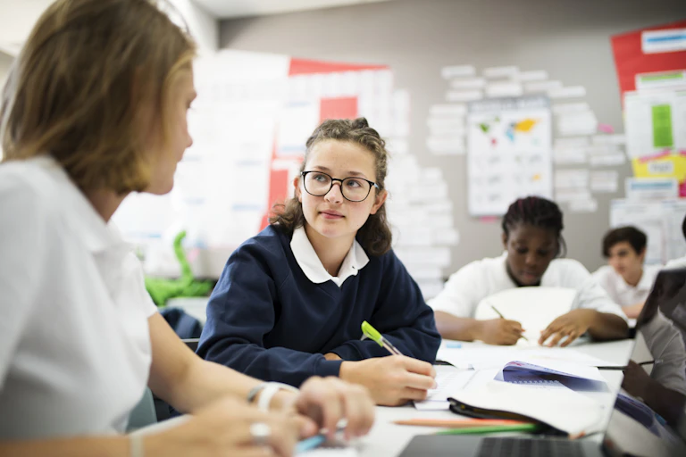 High school students work with notebooks and pens in a classroom