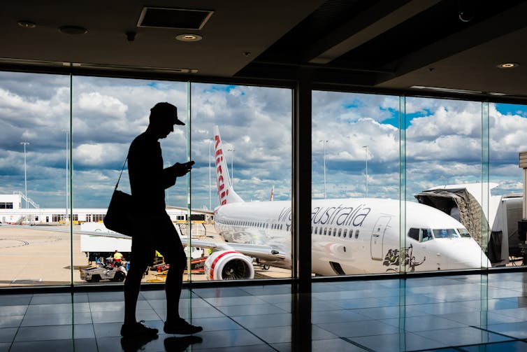 Silhouette of man in front of airport window