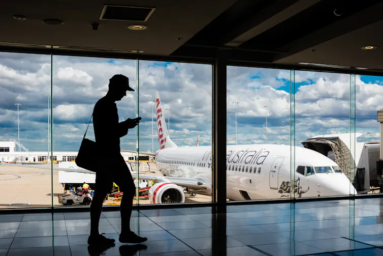 Silhouette of man in front of airport window